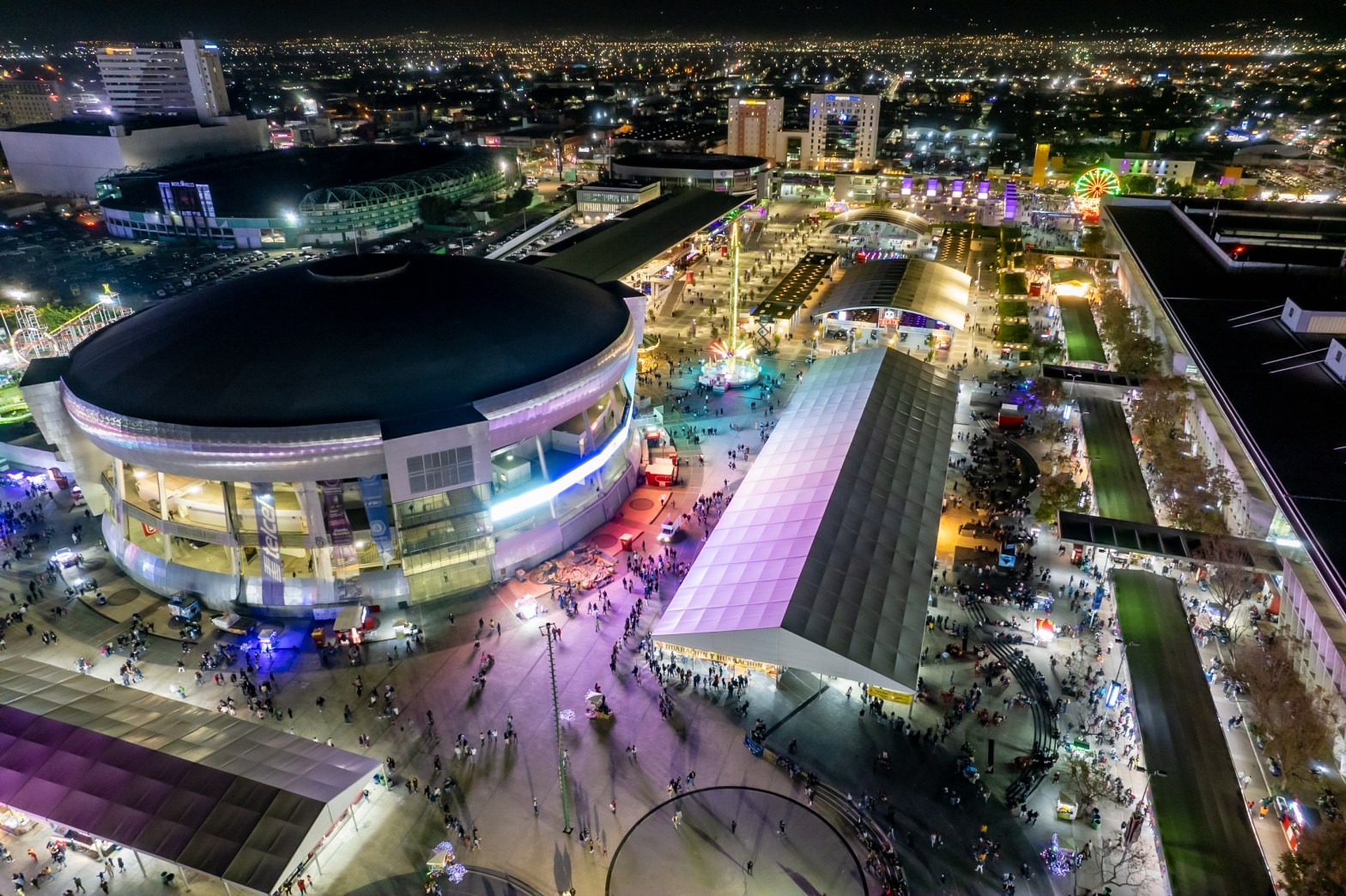 Vista aérea nocturna del Distrito León mostrando su infraestructura para eventos, actividades recreativas y alta afluencia de visitantes.